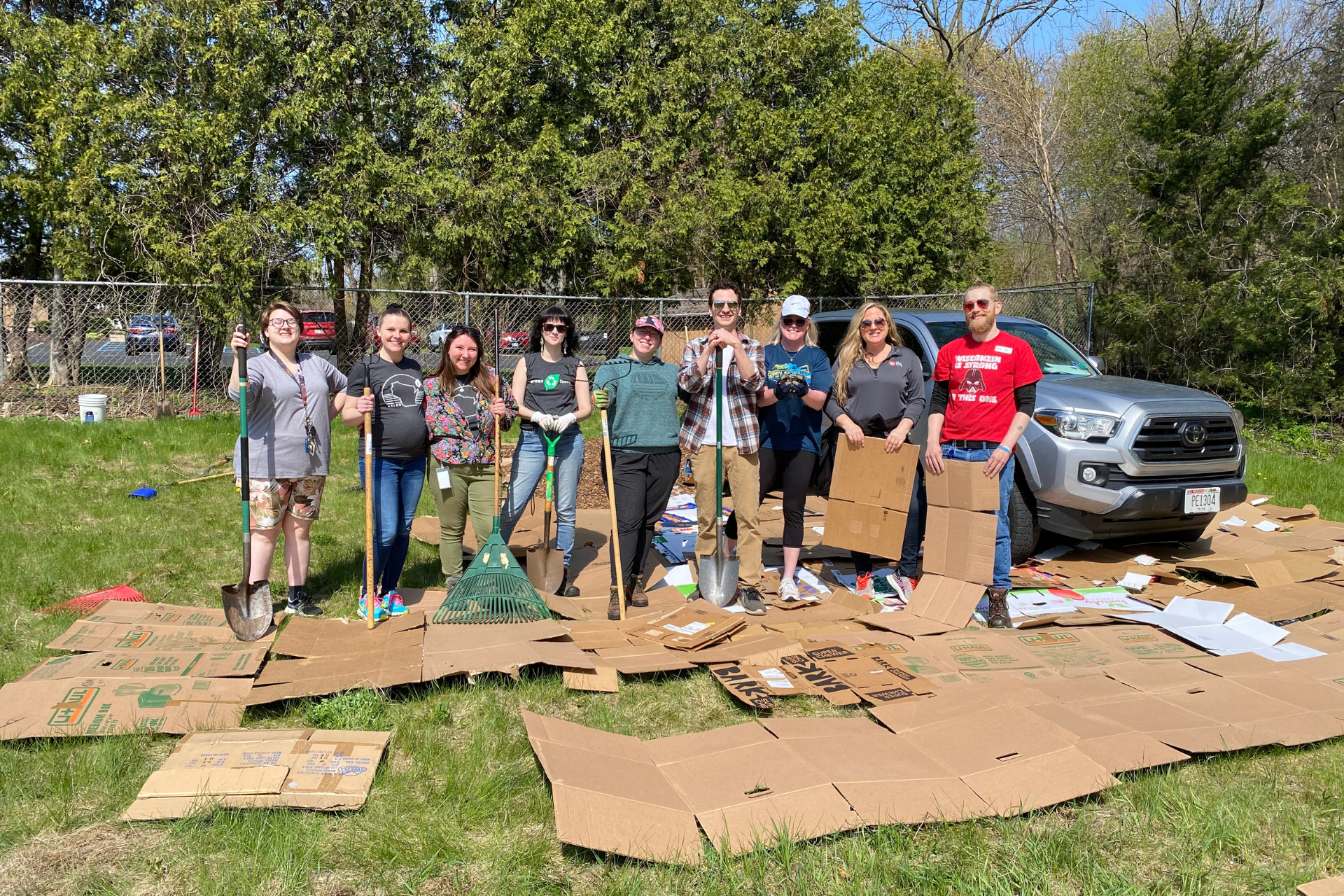 A group of UW Credit Union employees hold gardening tools.