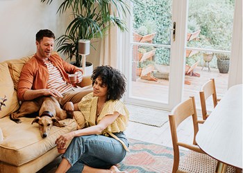 Couple enjoying their afternoon in their living room with their dog