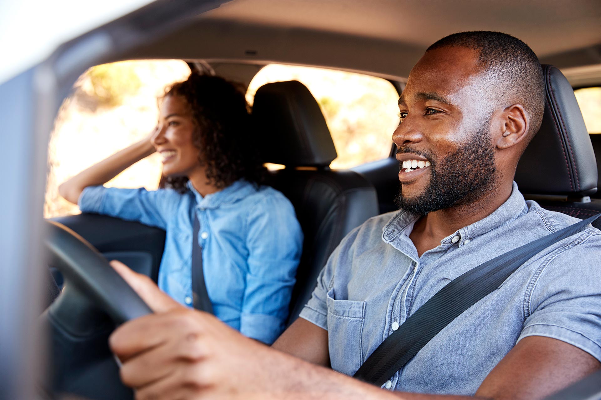 Young black couple driving their vehicle after refinancing their auto loan with UW Credit Union.