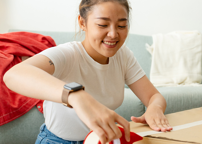 Young women unpacking a box in her new apartment.