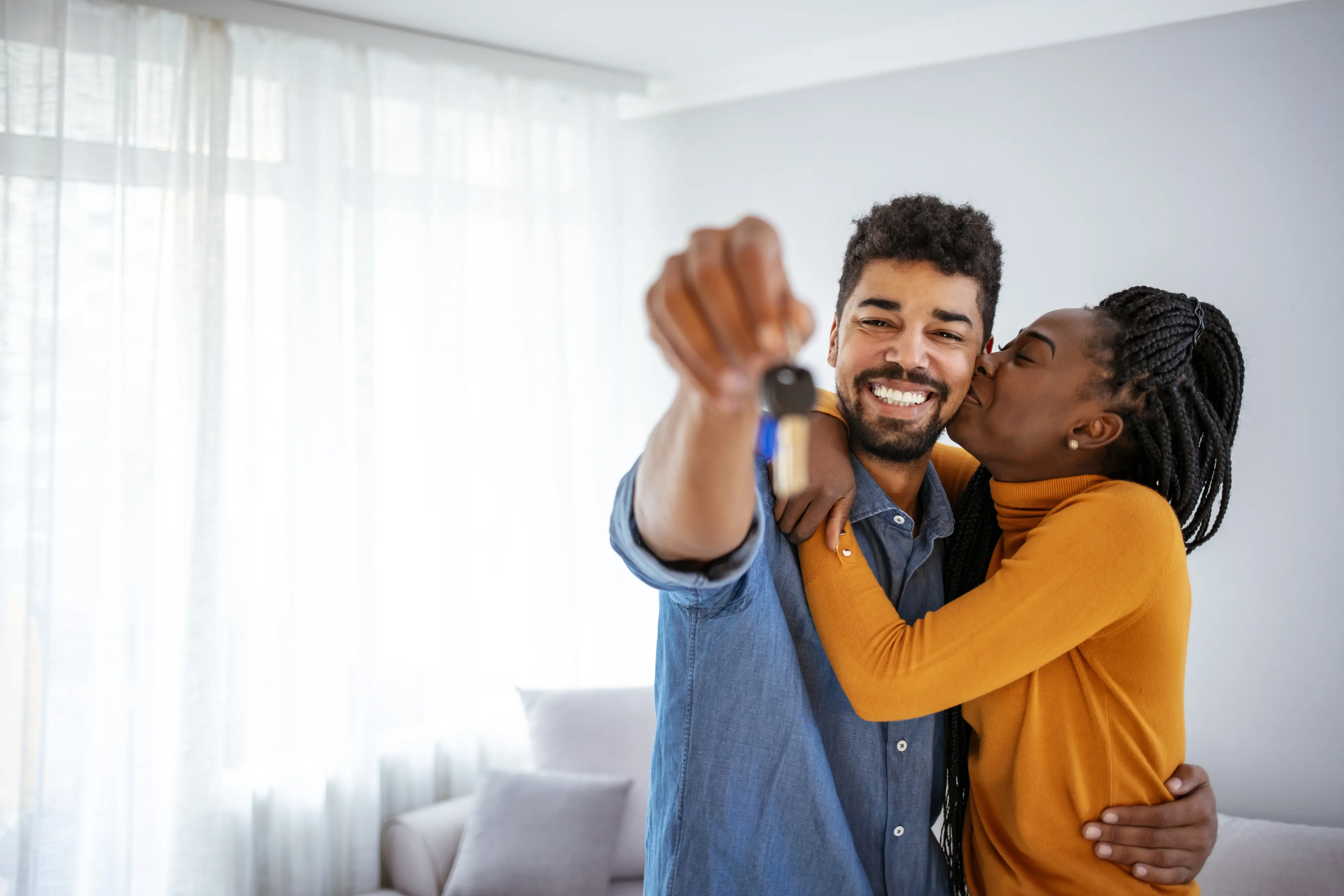 Happy new homeowners hugging each other and showing their keys Happy new homeowners hugging each other and showing their keys