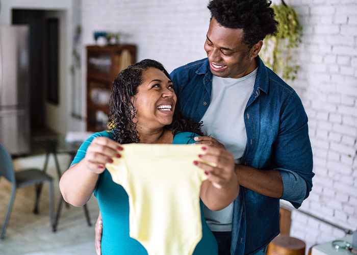 smiling expectant couple with credit union savings account