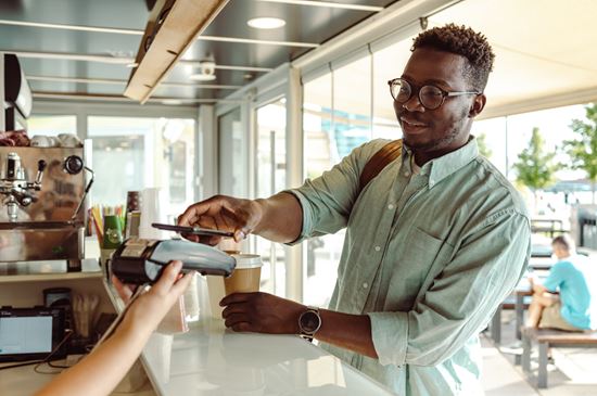 A man taps his card at a POS machine of a store.