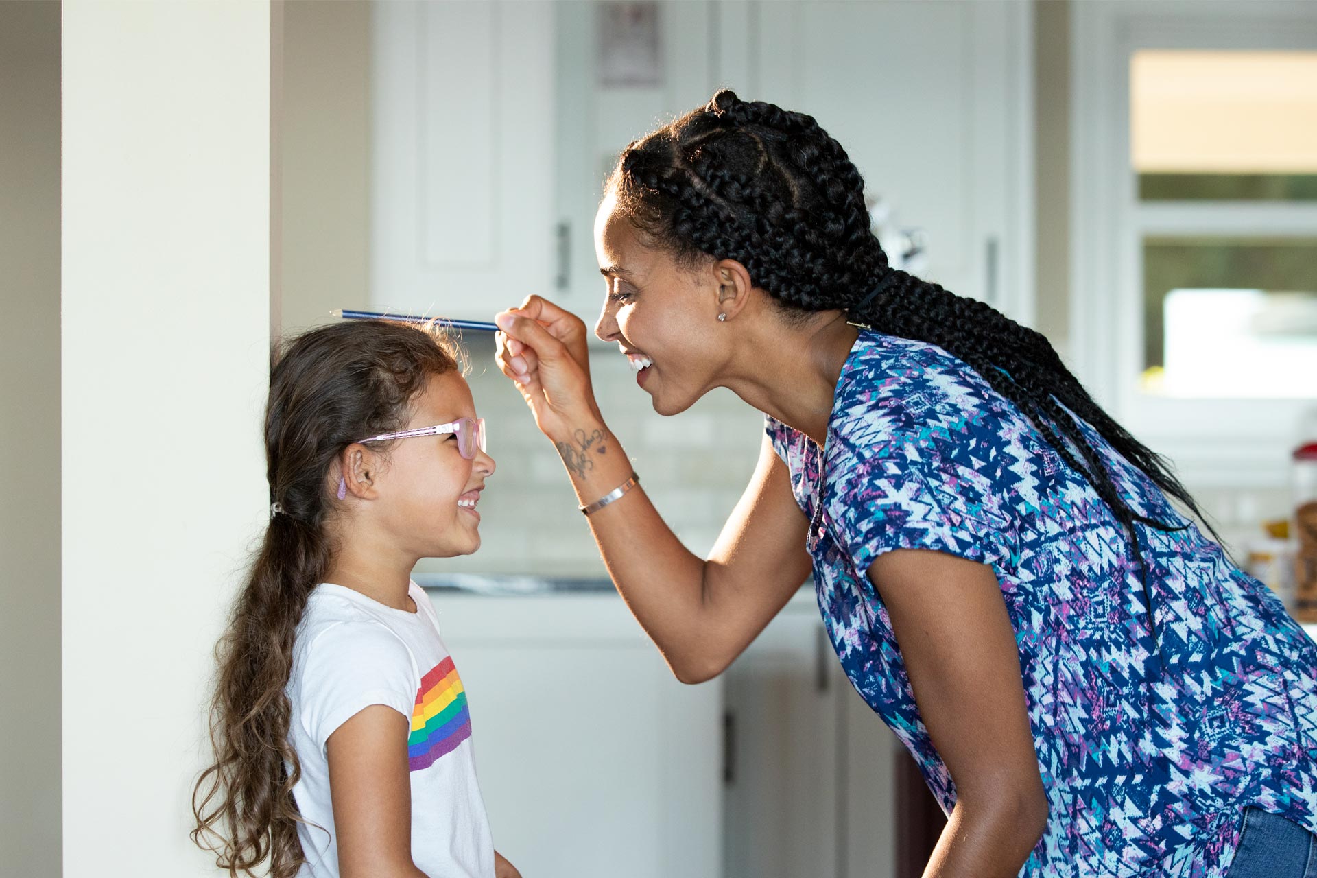 Mother with young daughter measuring her growth - now is the time to start saving for their college education. 