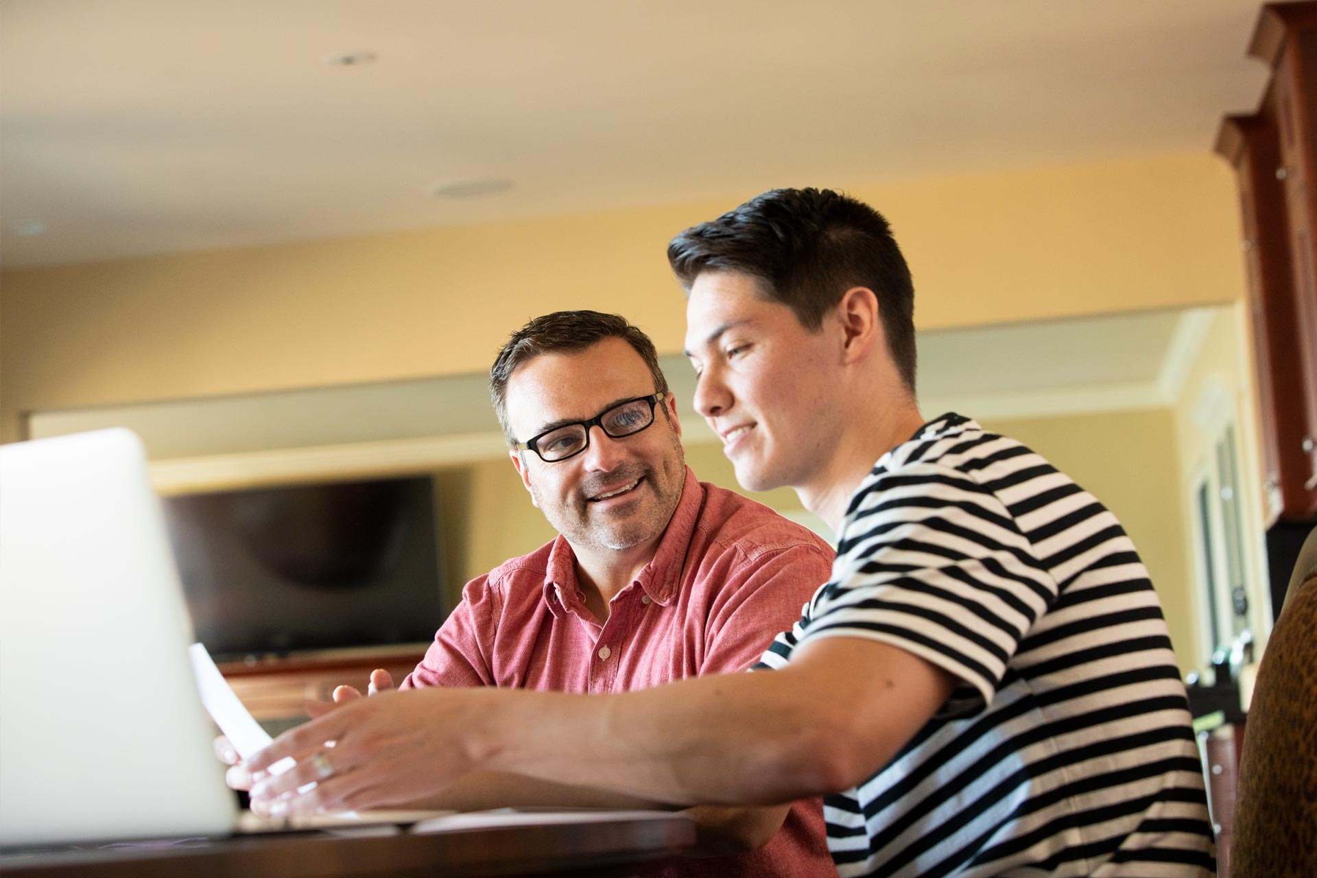 Father and son working at computer to complete FAFSA application for Federal Student Aid.