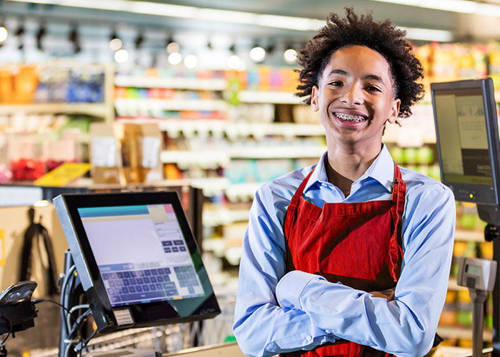 A teen smiles at his first job after opening a checking account to deposit his earnings