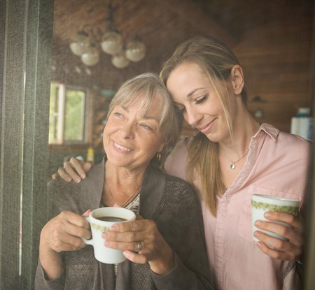 Mother and daughter drink coffee and discuss saving money with UW Credit Union